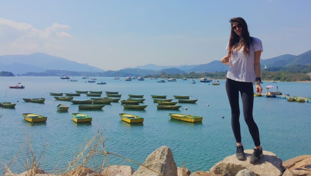 woman standing on a rock with small yellow boats on the background