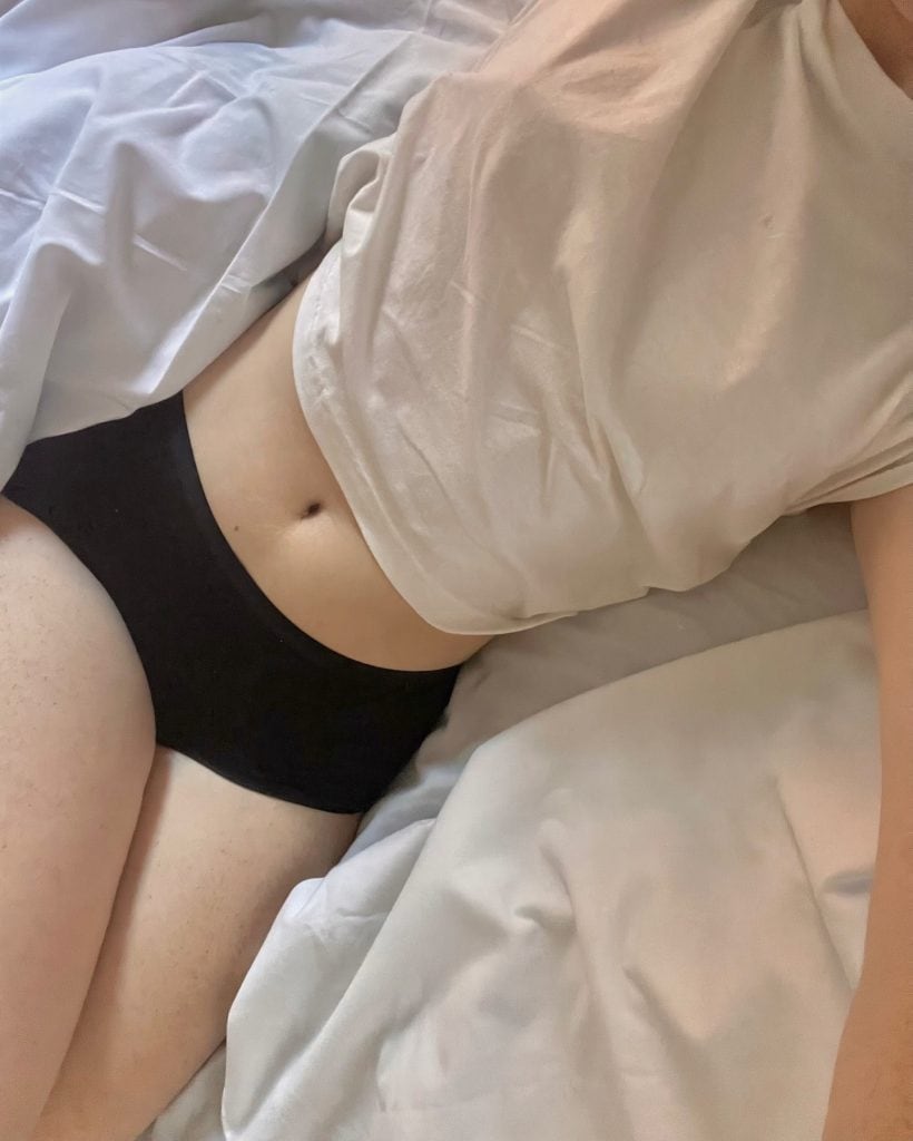 woman on the bed stretching wearing undies and t-shirt