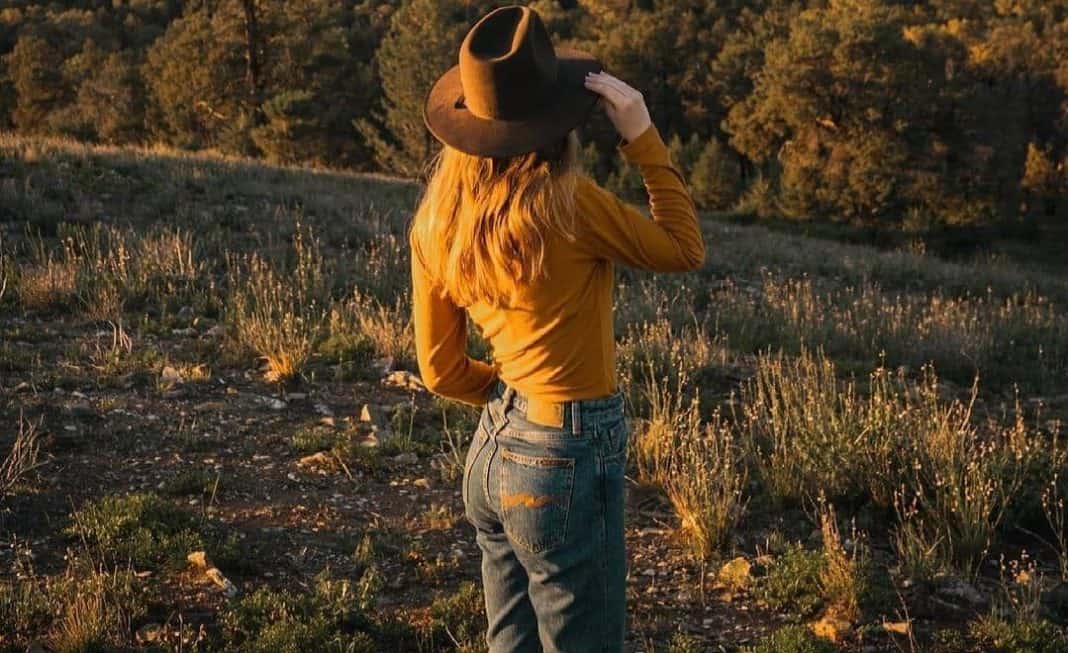woman watching the mountains while holding her cowboy hat