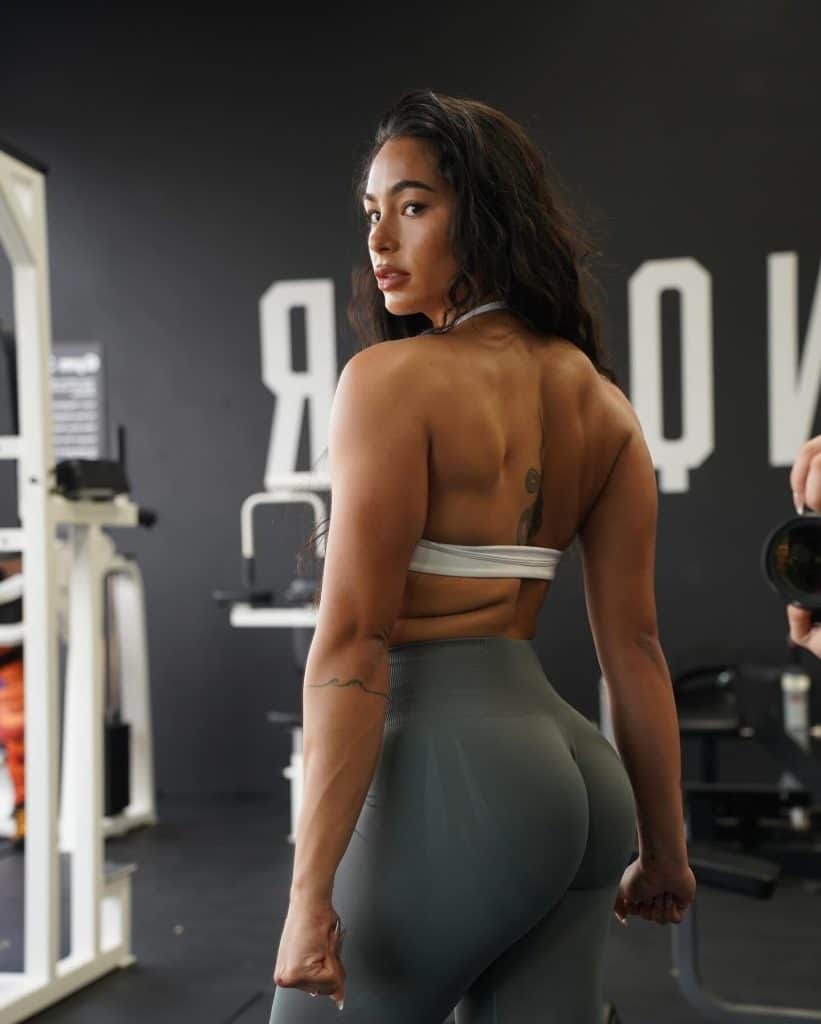 woman in a gym checking her back muscles