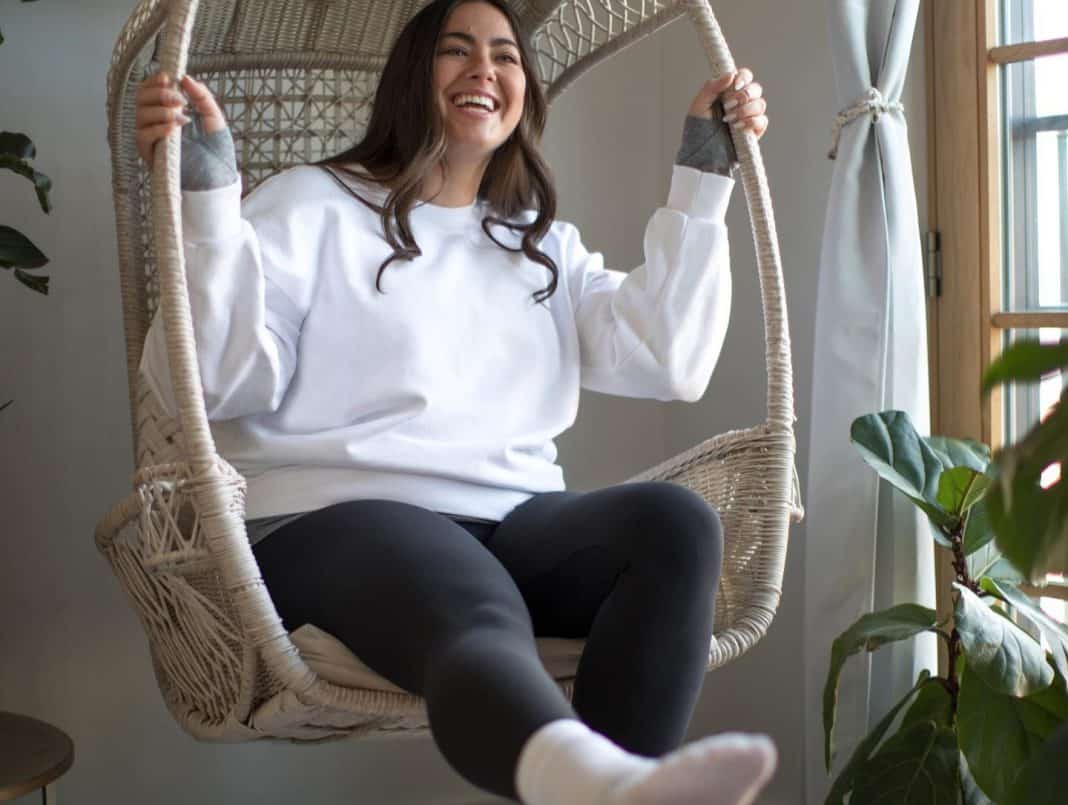 woman sitting on a swing wearing a sweater and leggings
